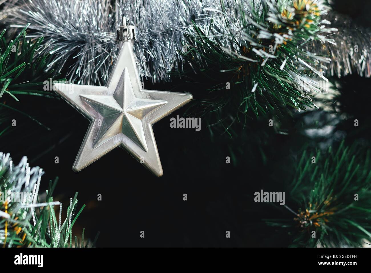 Silver star on artificial Christmas tree with silver tinsel garland ...