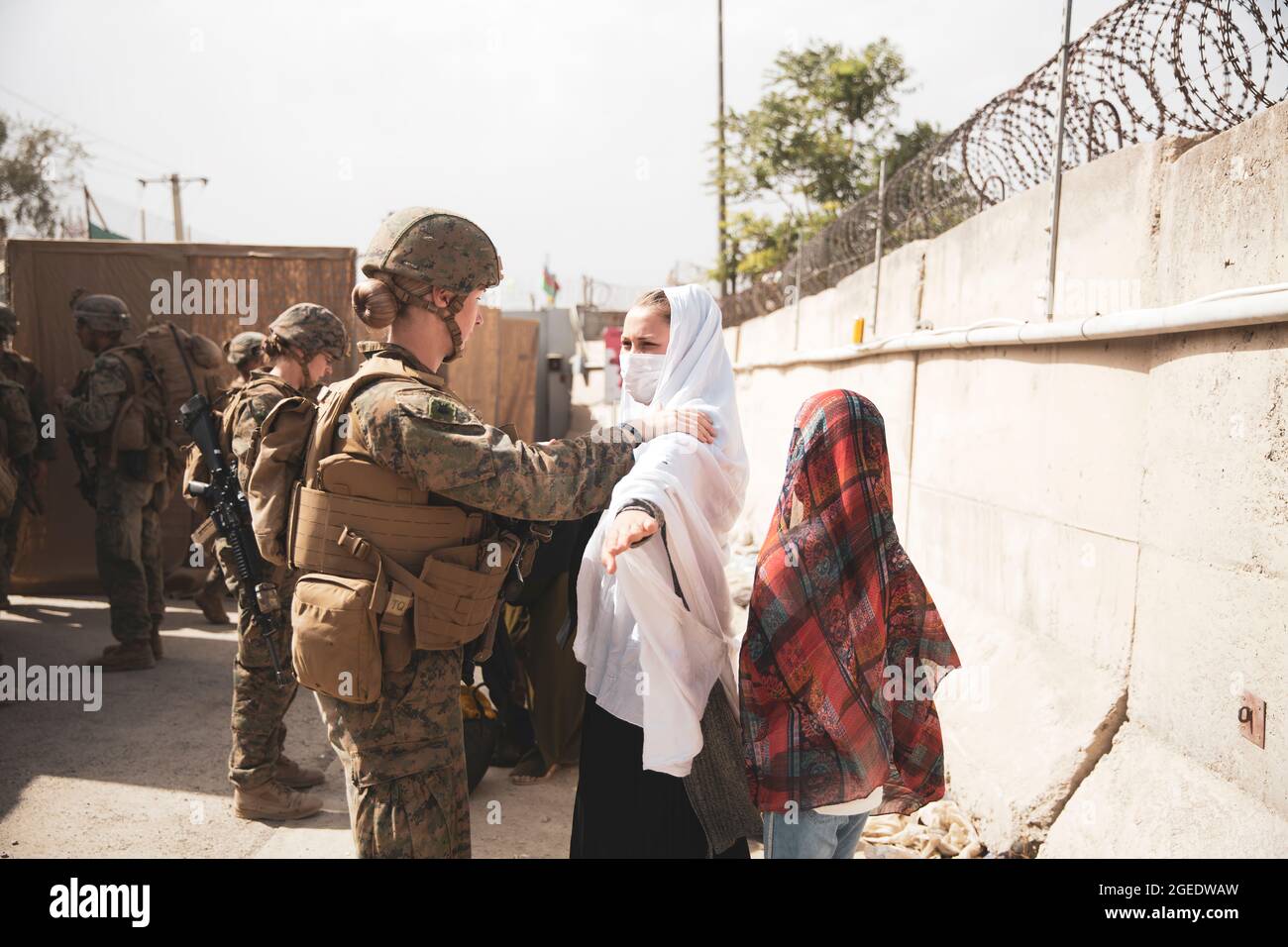 A Marine checks two civilians during processing through an Evacuee Control Checkpoint (ECC) during an evacuation at Hamid Karzai International Airport, Kabul, Afghanistan, Aug. 18. U.S. Marines are assisting the Department of State with an orderly drawdown of designated personnel in Afghanistan. (U.S. Marine Corps photo by Staff Sgt. Victor Mancilla) Stock Photo