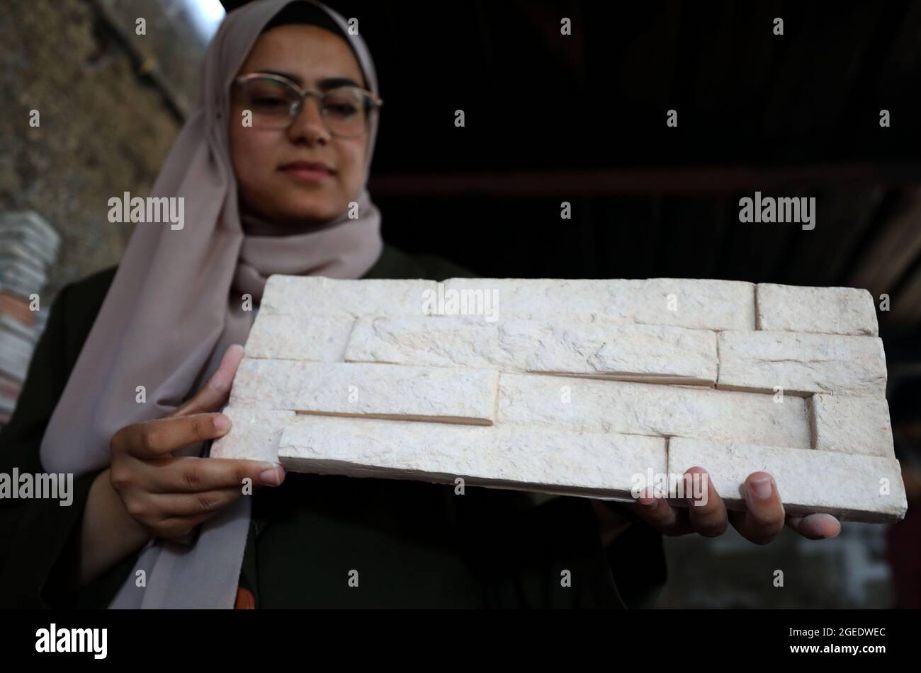 Tulkarem. 12th Aug, 2021. Rawan Rajab displays eco-friendly building stones at her workshop in the West Bank City of Tulkarem, Aug. 12, 2021. TO GO WITH 'Feature: Young Palestinian woman turns glass waste into eco-friendly building stones' Credit: Ayman Nobani/Xinhua/Alamy Live News Stock Photo