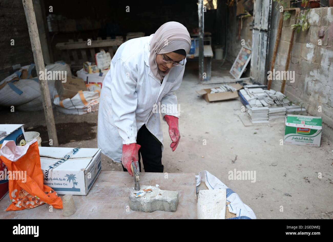 Tulkarem. 12th Aug, 2021. Rawan Rajab works on turning the waste of glass into eco-friendly building stones at her workshop in the West Bank City of Tulkarem, Aug. 12, 2021. TO GO WITH 'Feature: Young Palestinian woman turns glass waste into eco-friendly building stones' Credit: Ayman Nobani/Xinhua/Alamy Live News Stock Photo