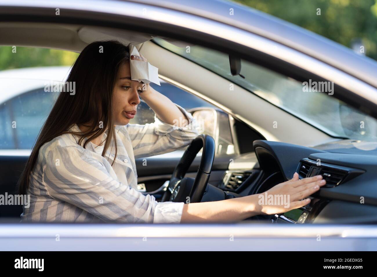 Exhausted young woman suffer from heat inside car with broken air