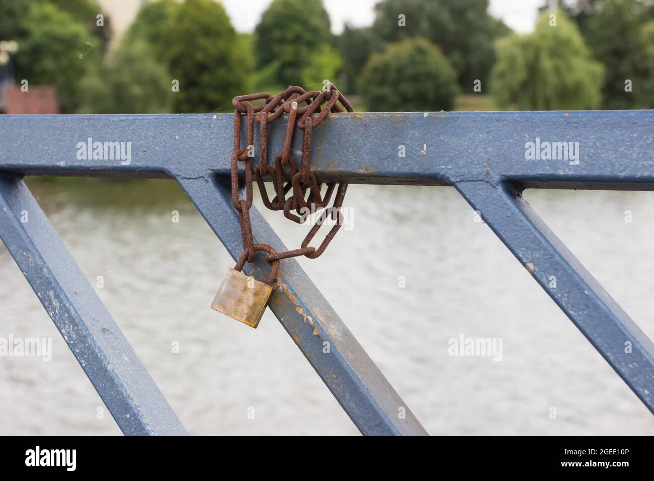 Closeup of a weathered chain and lock, locked on a railing near a lake ...