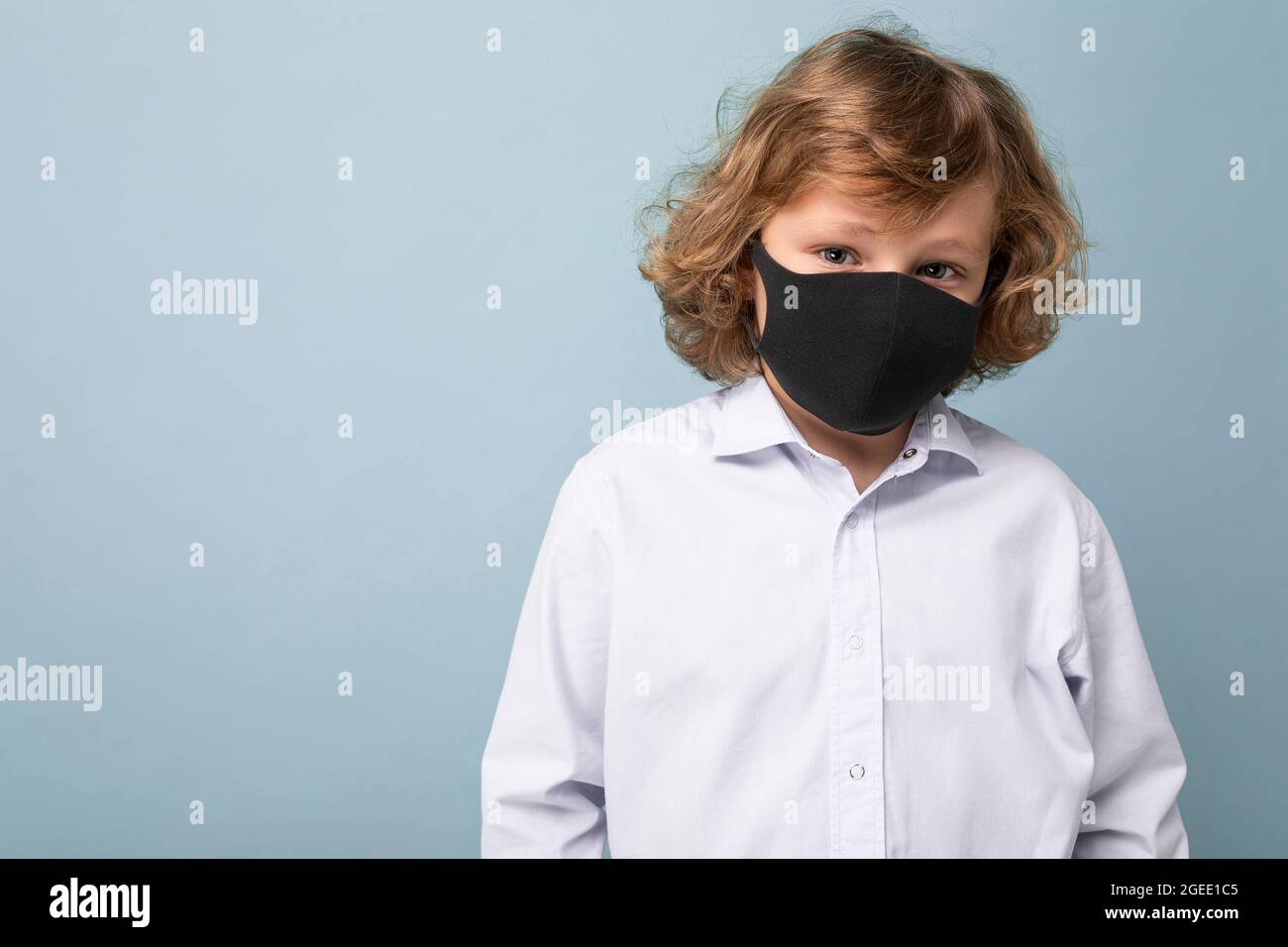 Photo of handsome curly blonde little boy in medical black mask ...