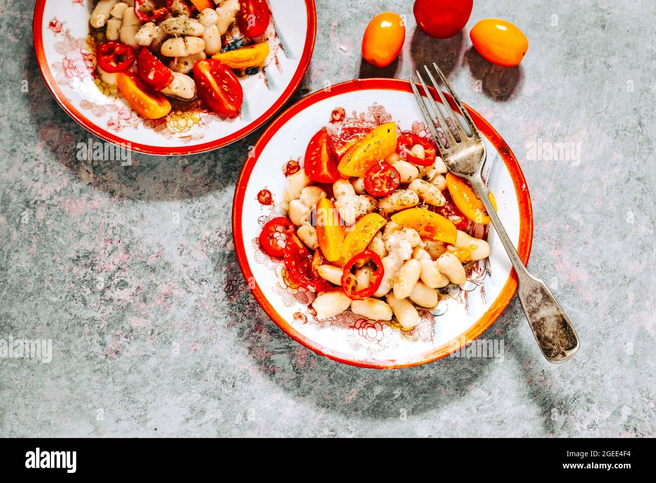 Tomato and Cannelloni Bean Salad with Red and Yellow Tomatoes on a Plate Stock Photo