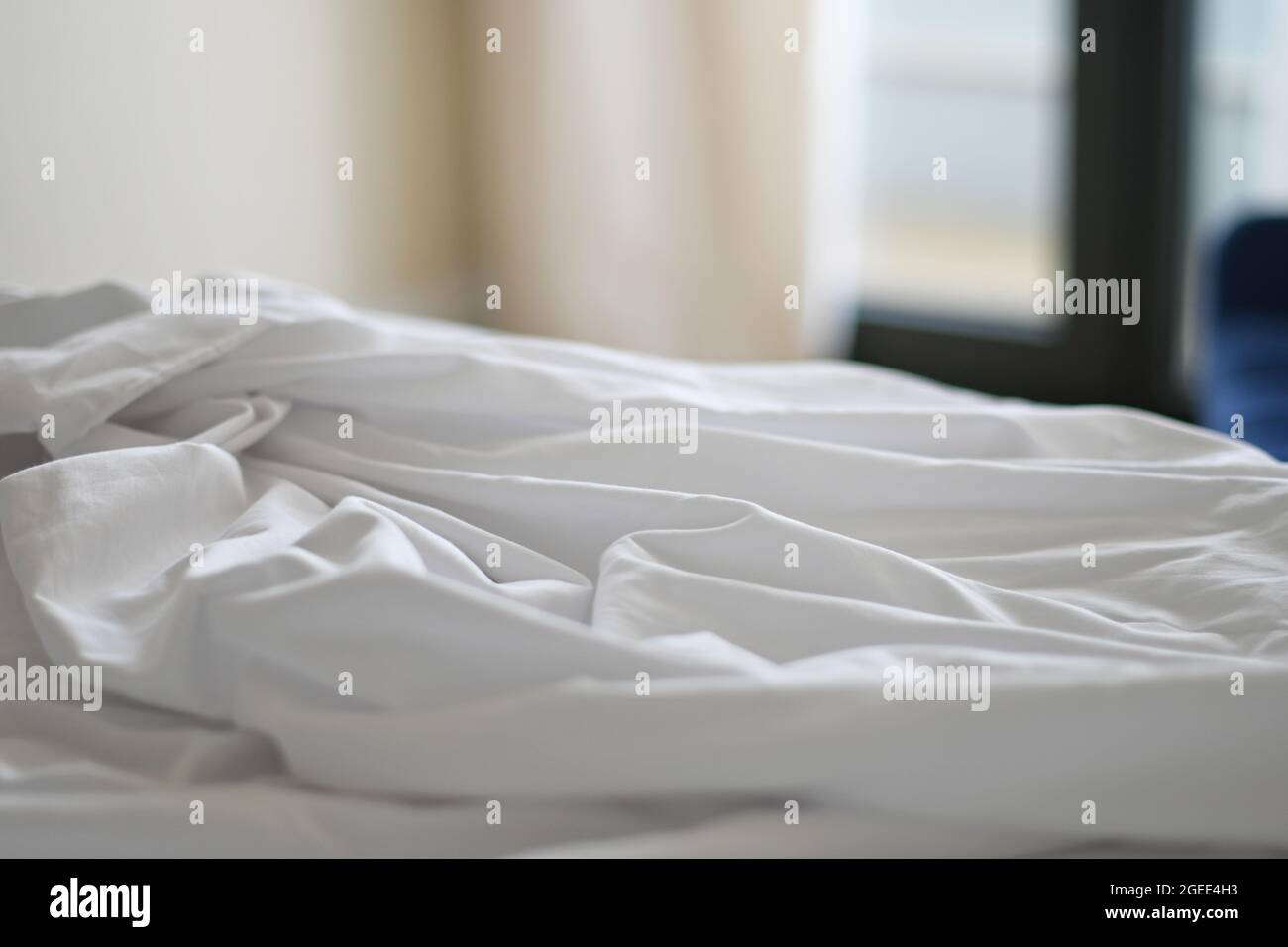 Unmade bed with crumpled bed sheet. Shallow depth of field Stock Photo