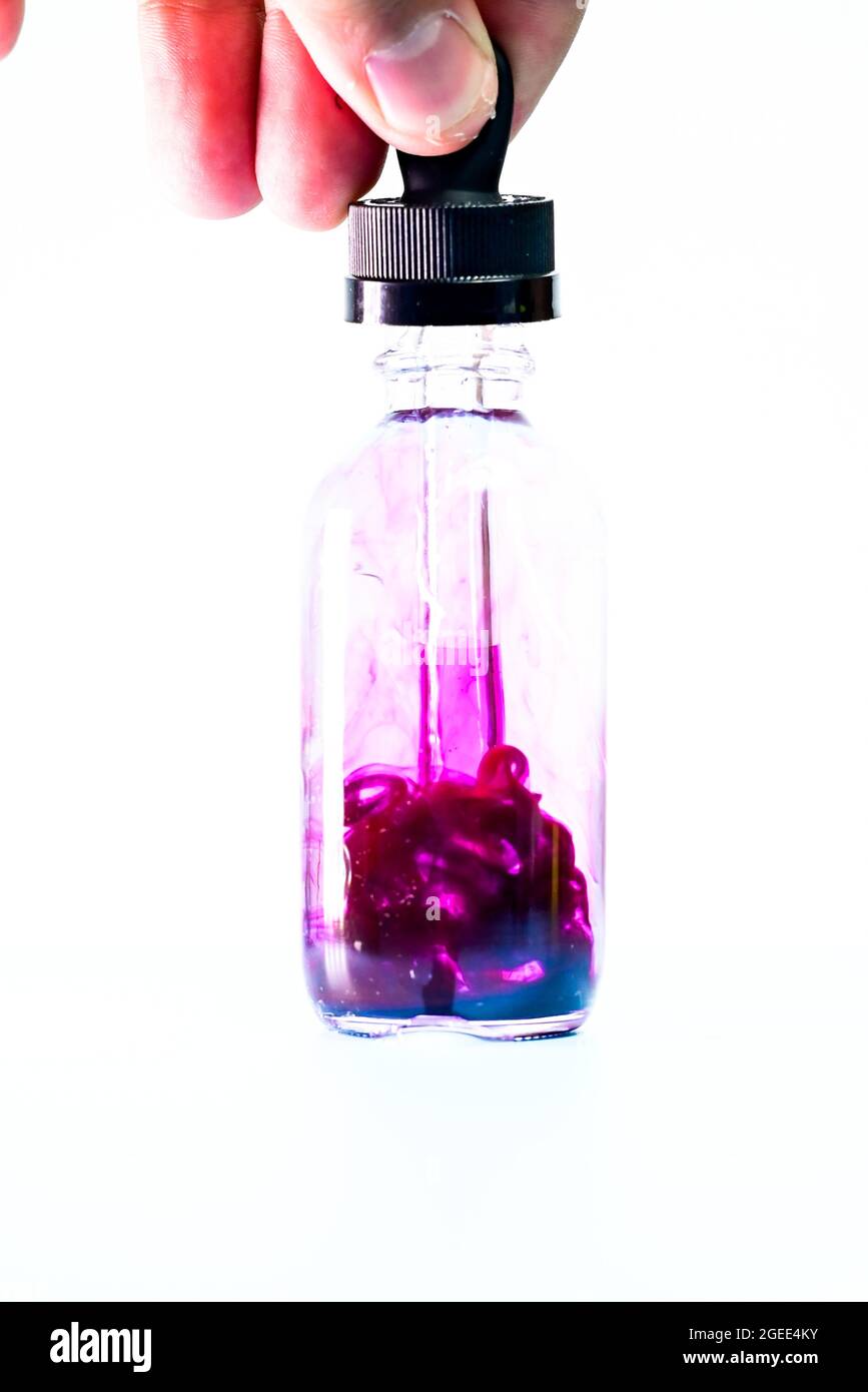 glass flask with purple paint on white background Stock Photo