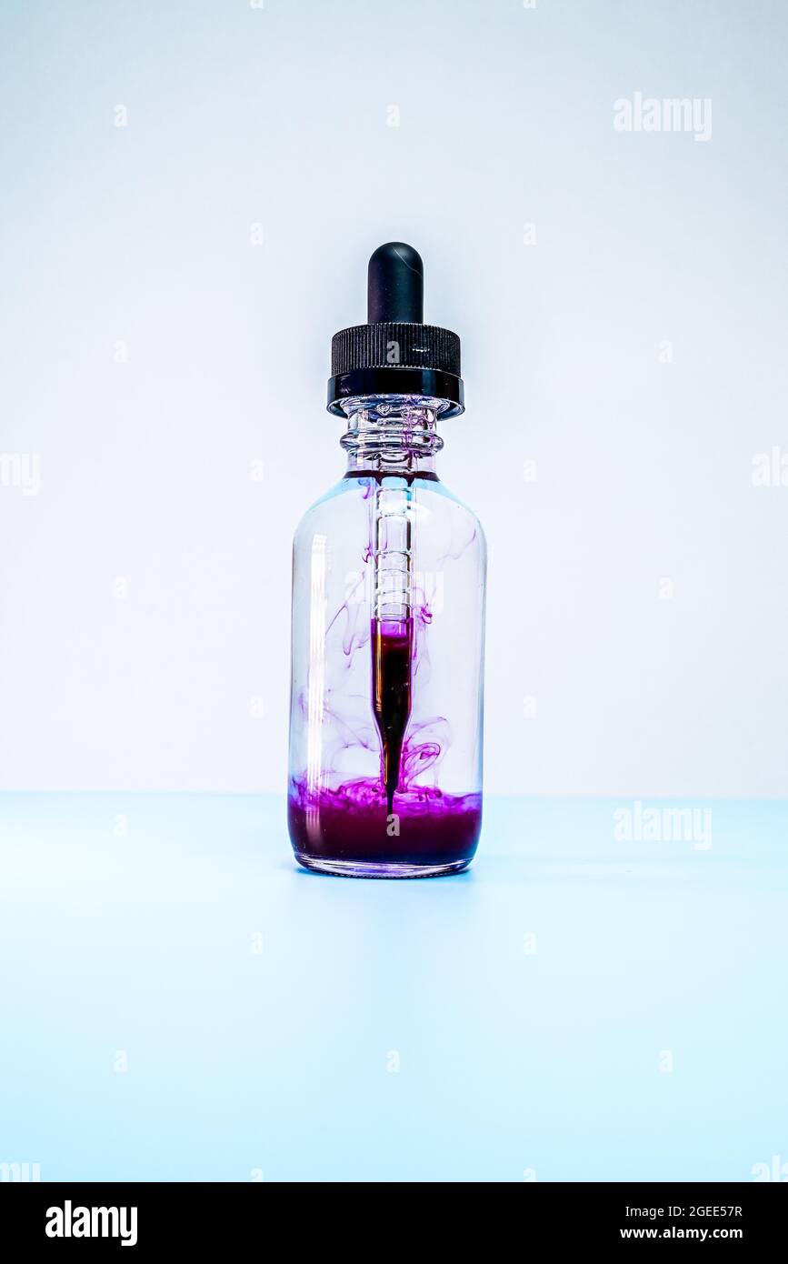 glass flask with purple paint on white background Stock Photo