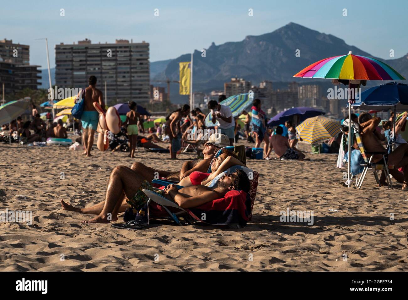 Tourists sunbathing enjoying a day with hot weather in San Juan Beach during summer. Stock Photo