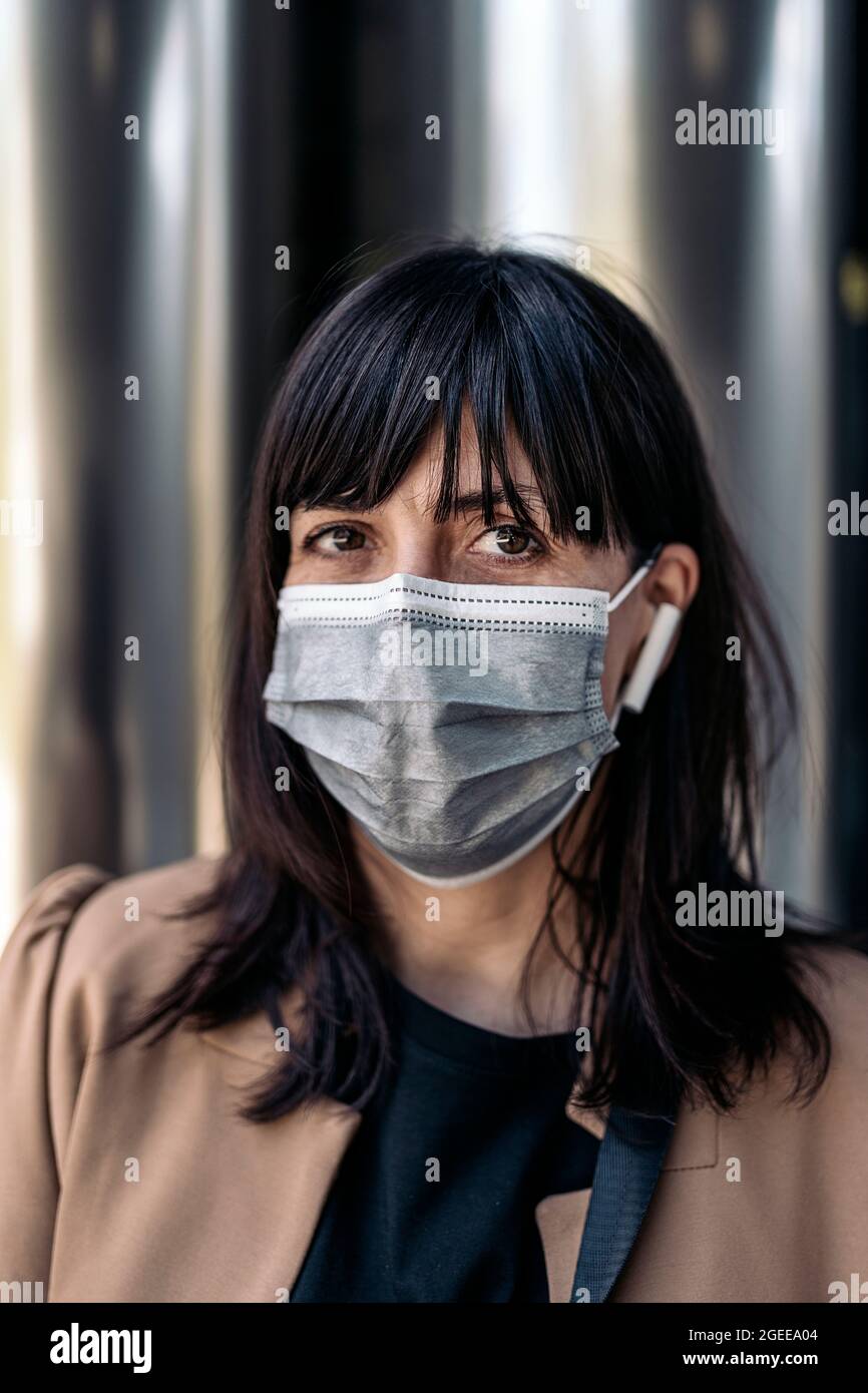 caucasian businesswoman wearing a face mask and earphones Stock Photo