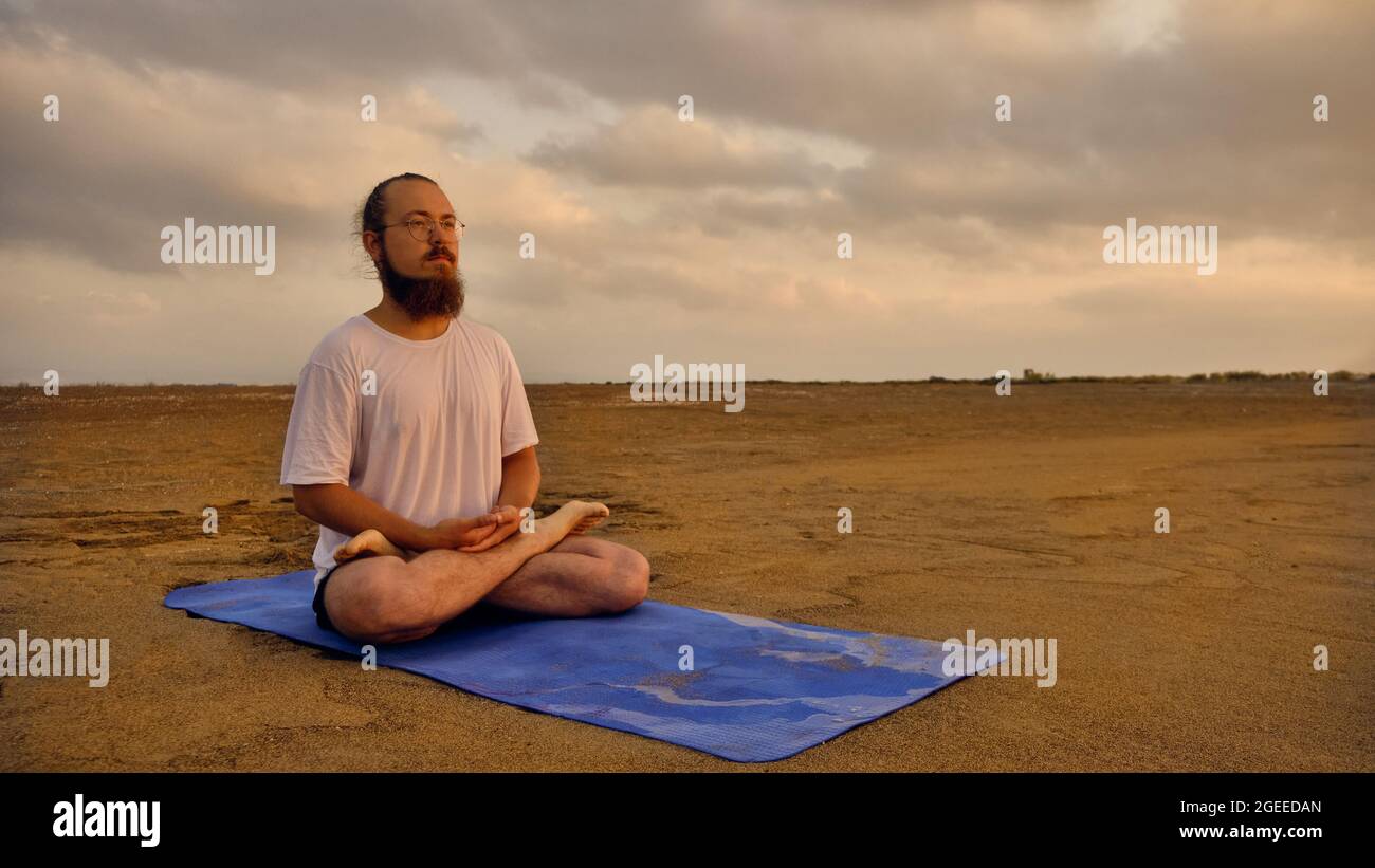 Man sits in lotus position at beach Stock Photo
