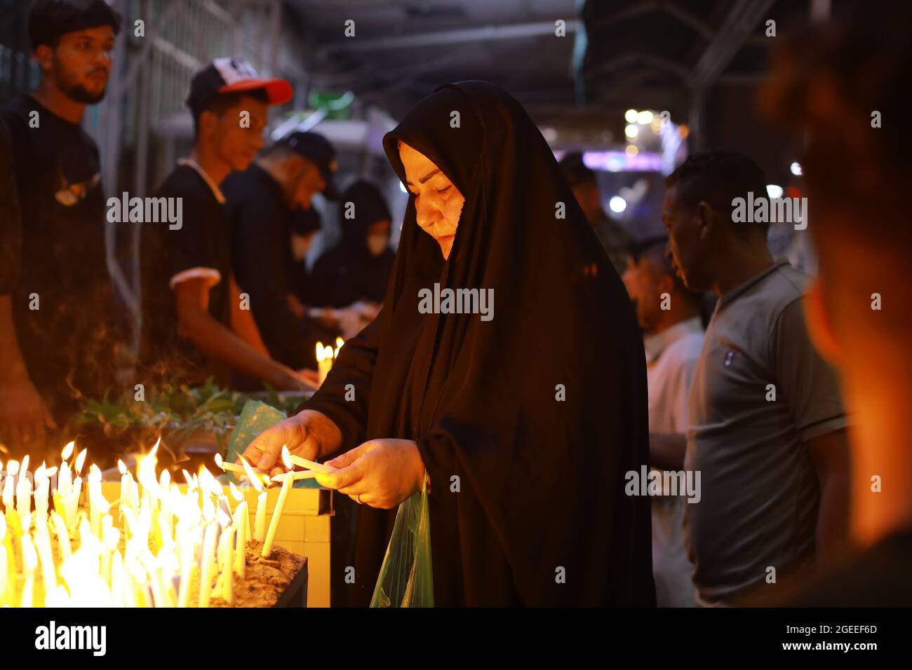 Karbala, Iraq. 19th Aug, 2021. A Shiite Muslim woman lights candles at the Imam Abbas shrine in Iraq's holy city of Karbala on Ashura Day on the 10th of Muharram, the first month of the Islamic calendar. Muharram is considered a month of mourning and remembrance for Shiite Muslims around the world, in which they commemorate the martyrdom of the grandson of the Islamic prophet Mohammad, Husayn ibn Ali, who was killed in the 7th century Battle of Karbala. Credit: Ameer Al Mohammedaw/dpa/Alamy Live News Stock Photo