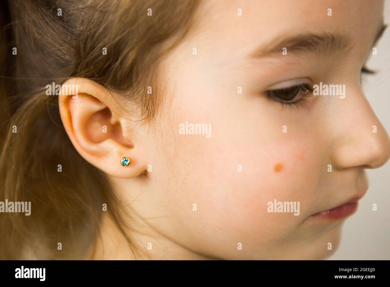 Ear piercing in a child a girl shows an earring in her ear made of a