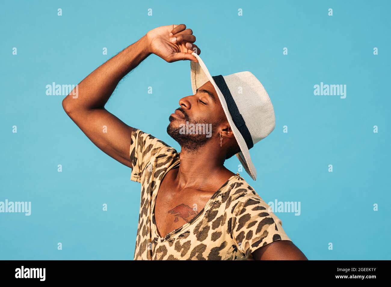 Side view of young stylish man with head up holding a straw hat with closed eyes Stock Photo