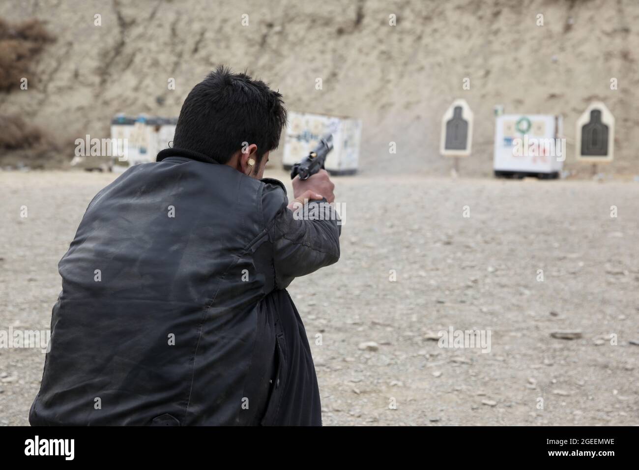 A man with the Afghan National Directorate of Security fires a M9 Beretta pistol on a small-arms range on Camp Parsa, Khowst province, Afghanistan, Jan. 30, 2013. U.S. Army soldiers assigned to Security Forces Advise and Assist Team 28, Task Force 3/101, planned the range and assisted the Afghan Uniformed Police and the NDS with safely practicing with their weapons. (U.S. Army photo by Sgt. Kimberly Trumbull / Released) Stock Photo