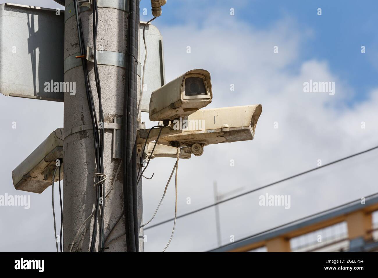 two old security surveillance cameras on street light pole on blue sky