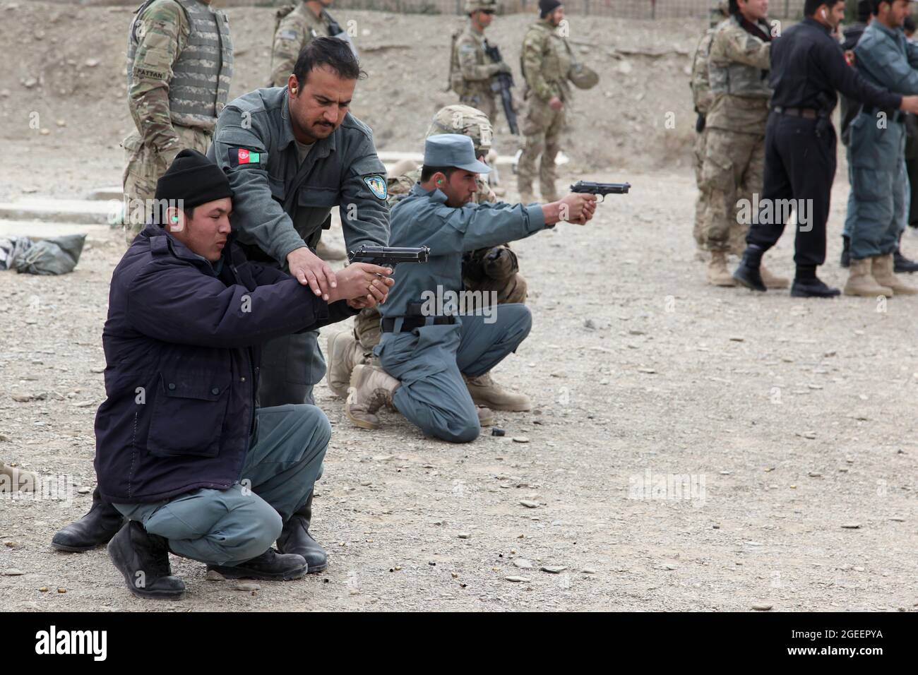 Afghan Uniformed Policemen, stationed in Khost city, help each other improve their skills while firing M-9 Beretta pistols on a small arms range on Camp Parsa, Khowst province, Afghanistan, Jan. 30, 2013. U.S. Army Soldiers assigned to Security Forces Advise and Assist Team 28, Task Force 3/101, planned the range and assisted the AUP with safely practicing with their weapons. (U.S. Army photo by Sgt. Kimberly Trumbull / Released) Stock Photo