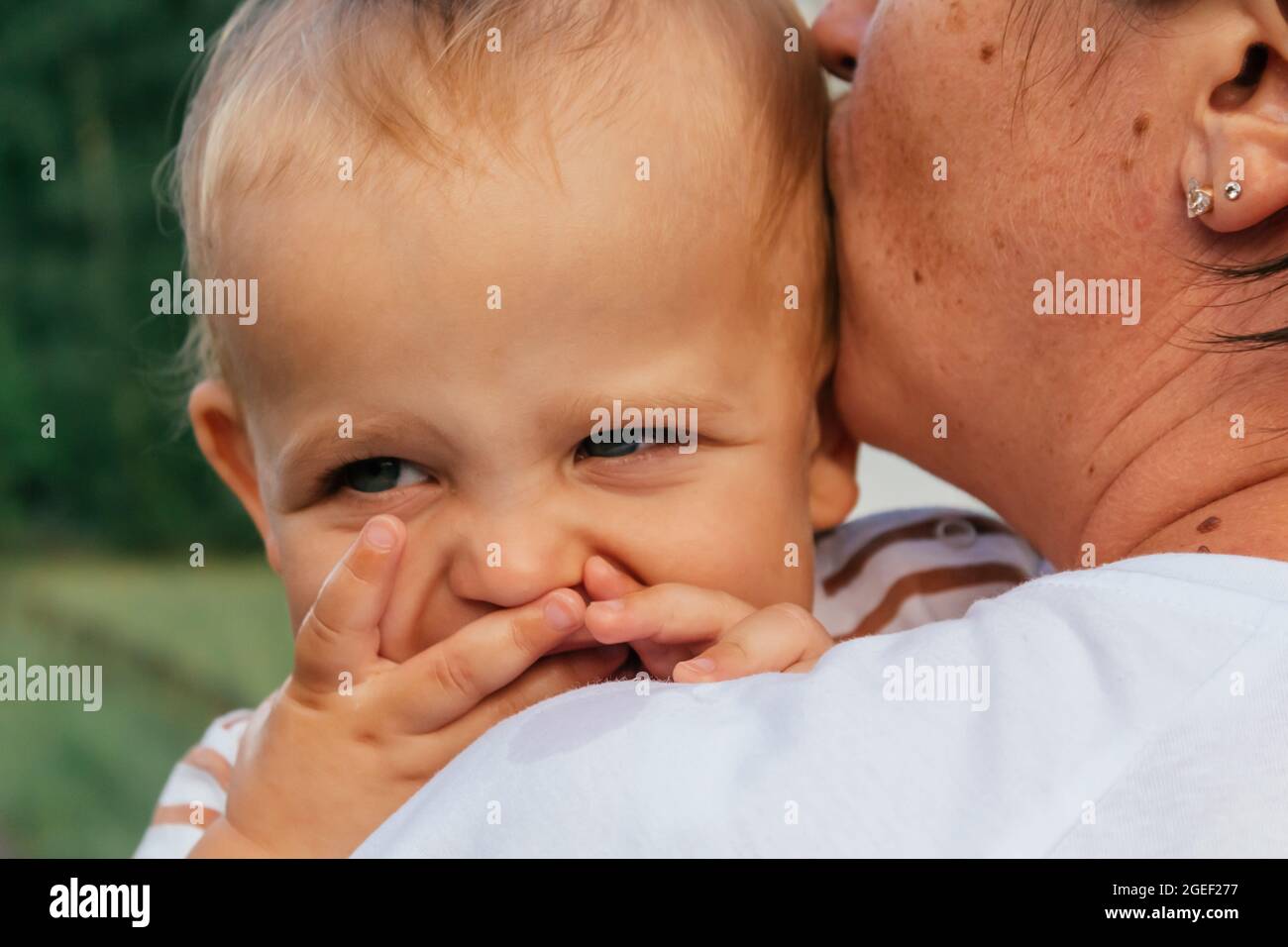 Little boy looks over his mother's shoulder. Stock Photo