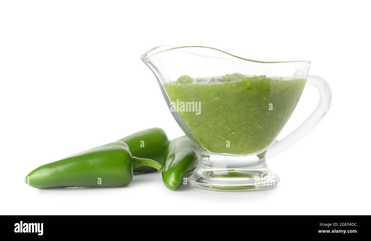 Jug of Tomatillo Salsa Verde sauce and jalapeno pepper on white background Stock Photo