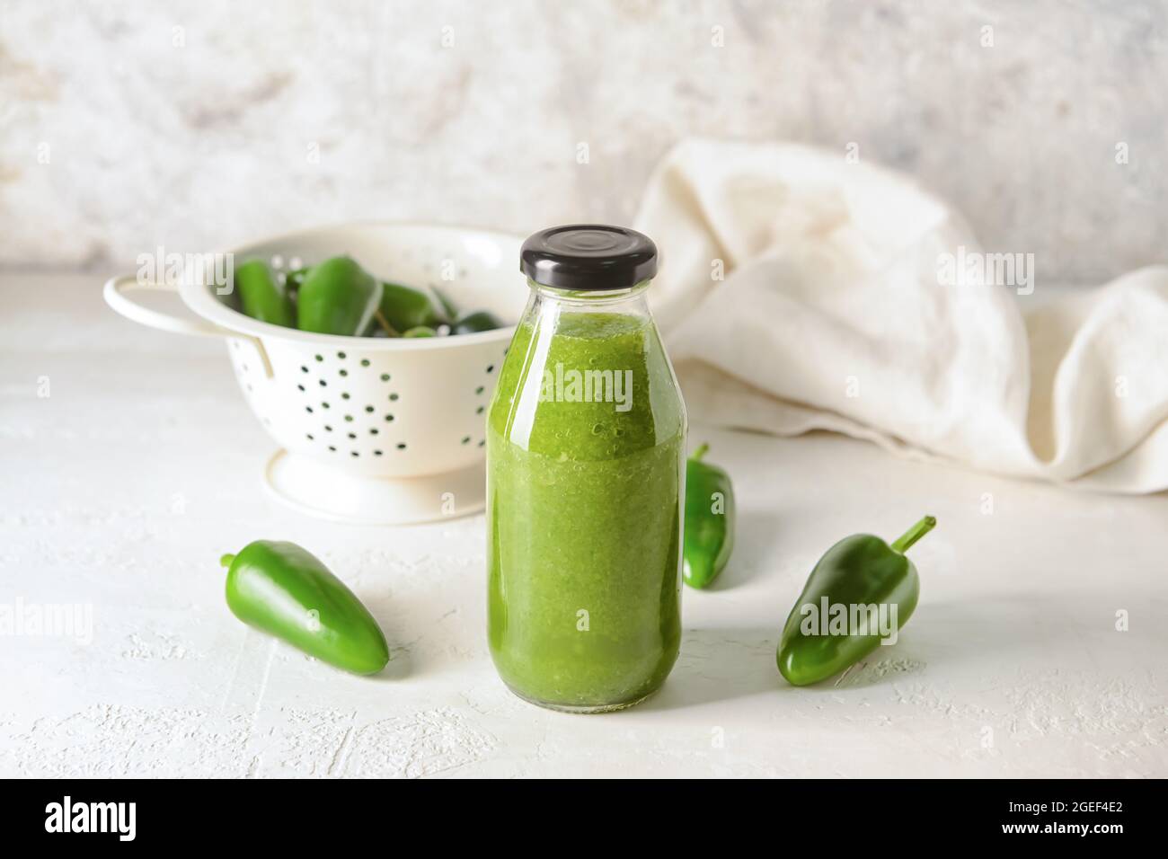 Bottle of Tomatillo Salsa Verde sauce and jalapeno pepper on light background Stock Photo