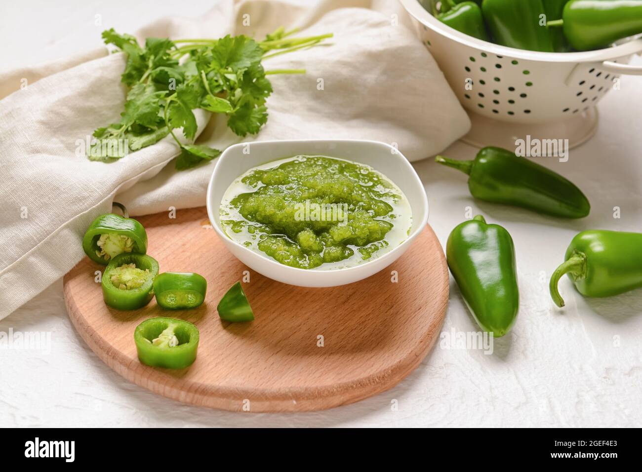 Bowl of Tomatillo Salsa Verde sauce and ingredients on light background Stock Photo