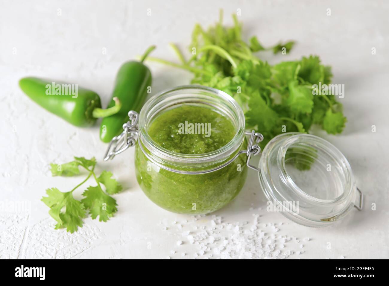 Glass jar of Tomatillo Salsa Verde sauce on light background Stock Photo