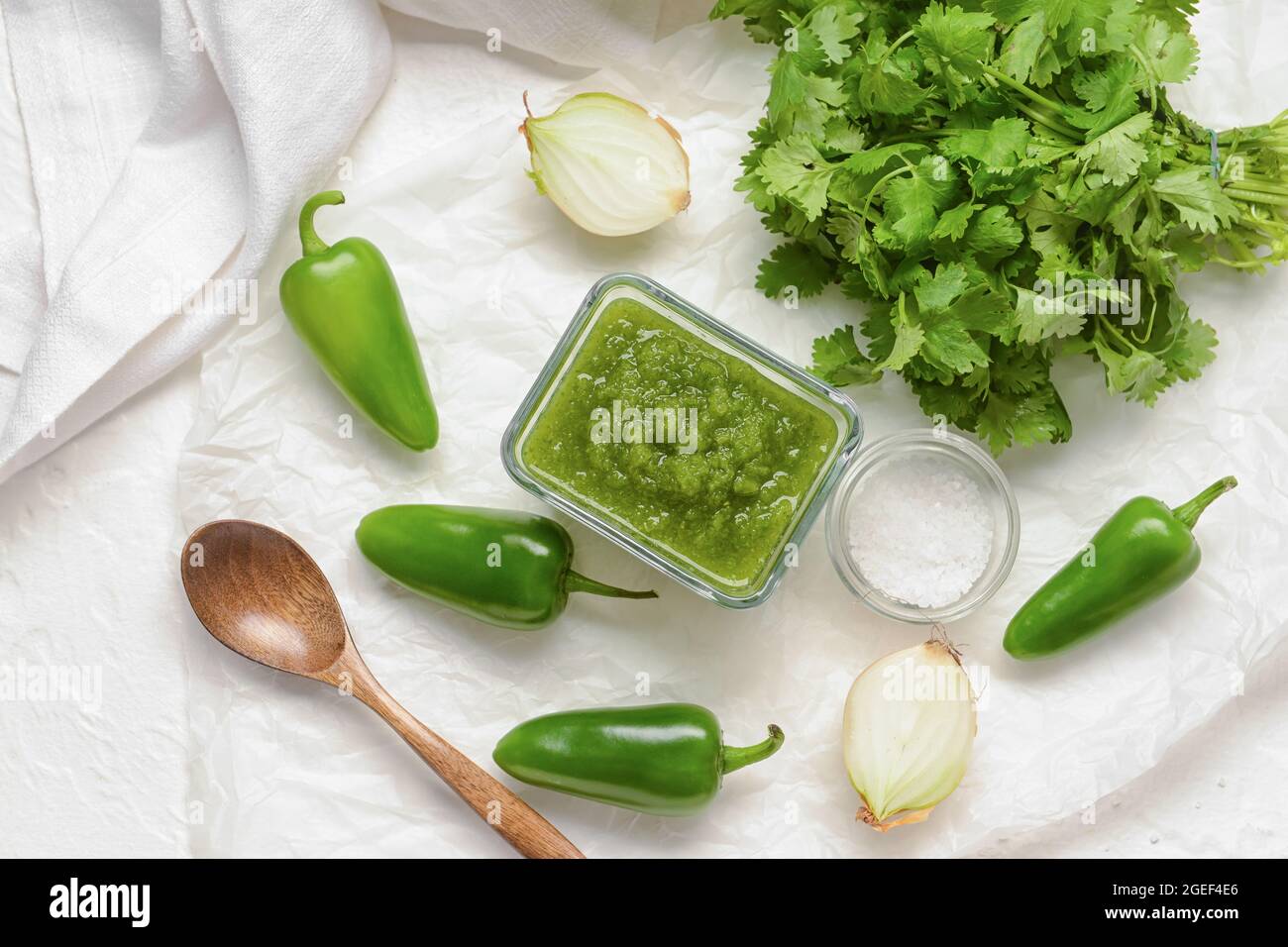 Bowl of Tomatillo Salsa Verde sauce and ingredients on light background Stock Photo
