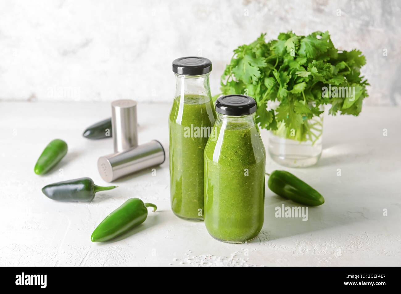 Bottles of Tomatillo Salsa Verde sauce and jalapeno pepper on light background Stock Photo