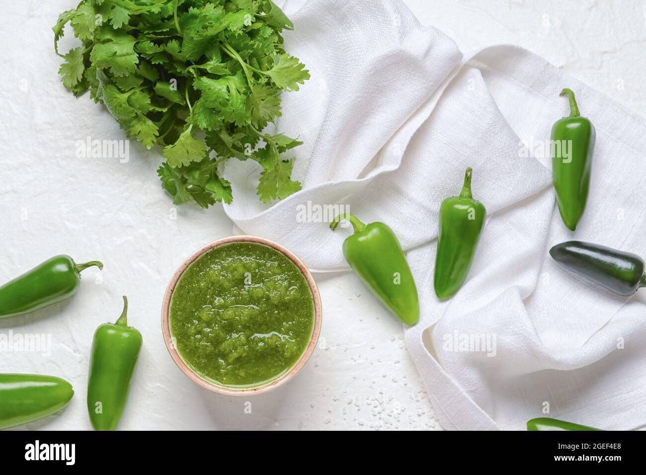 Bowl of Tomatillo Salsa Verde sauce and ingredients on light background Stock Photo