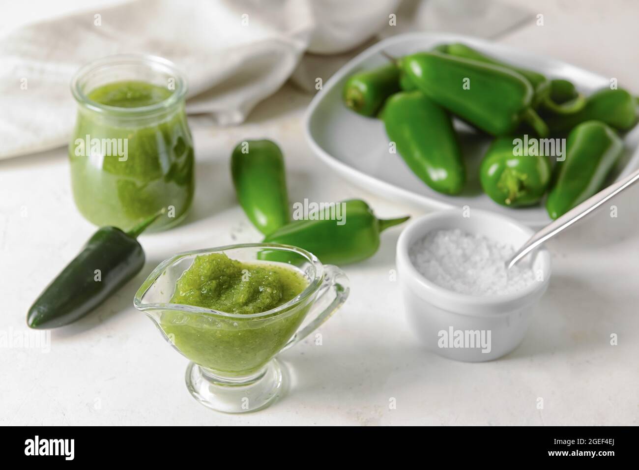 Jug of Tomatillo Salsa Verde sauce on light background Stock Photo