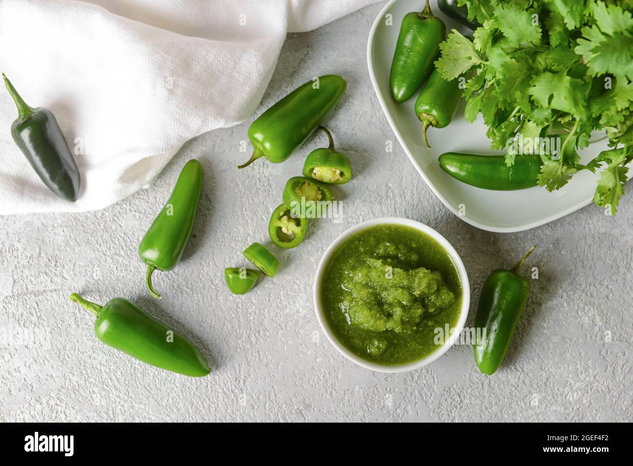 Bowl of Tomatillo Salsa Verde sauce and ingredients on light background Stock Photo
