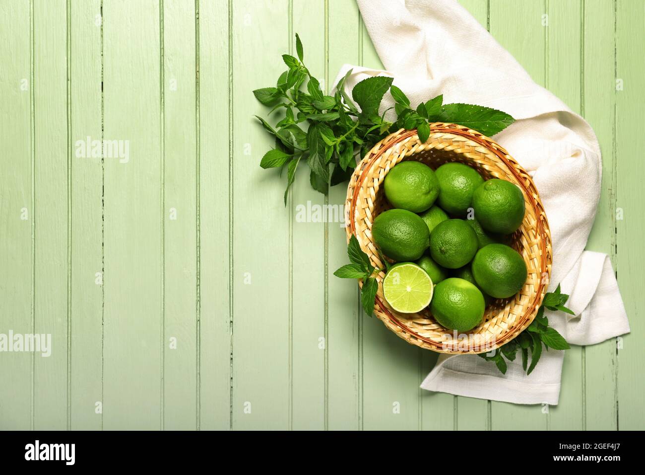 Basket with tasty limes on color wooden background Stock Photo - Alamy