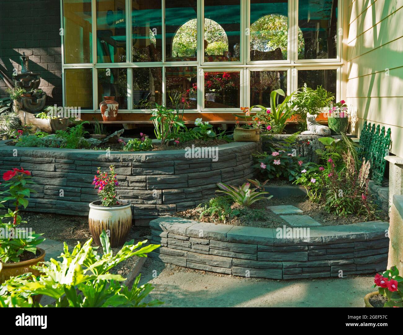 Garden feature with decorative curved brick retaining walls surrounding raised garden beds in a fernery, in Australia Stock Photo