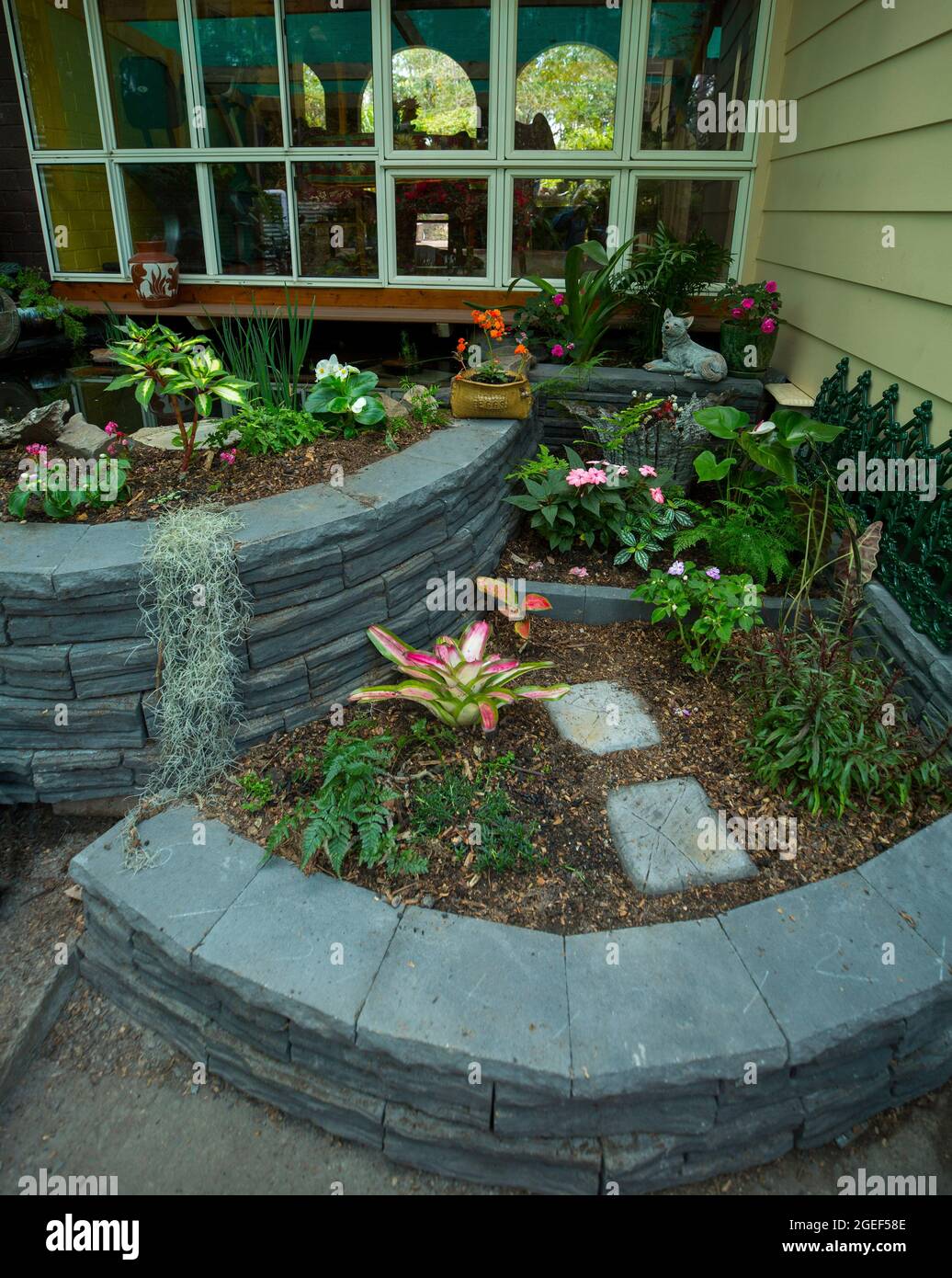 Garden feature with decorative curved brick retaining walls surrounding garden beds in a  fernery, in Australia Stock Photo