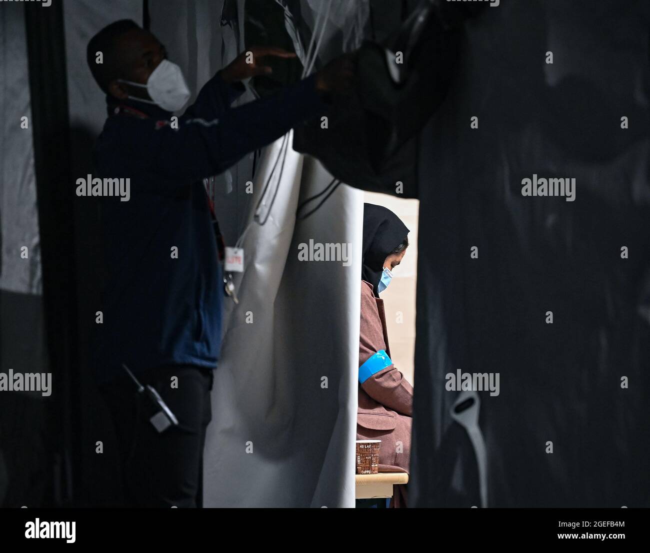 Doberlug Kirchhain, Germany. 20th Aug, 2021. A woman, who arrived together with other local forces from Afghanistan early this morning at the grounds of the DRK Refugee Aid at the Initial Reception Centre, sits in a tent. Around 4:30 in the early morning, two buses from the airport in Frankfurt am Main arrived here at the Central Foreigners Authority of Brandenburg with almost 60 local forces from Afghanistan. Credit: Patrick Pleul/dpa-Zentralbild/dpa/Alamy Live News Stock Photo
