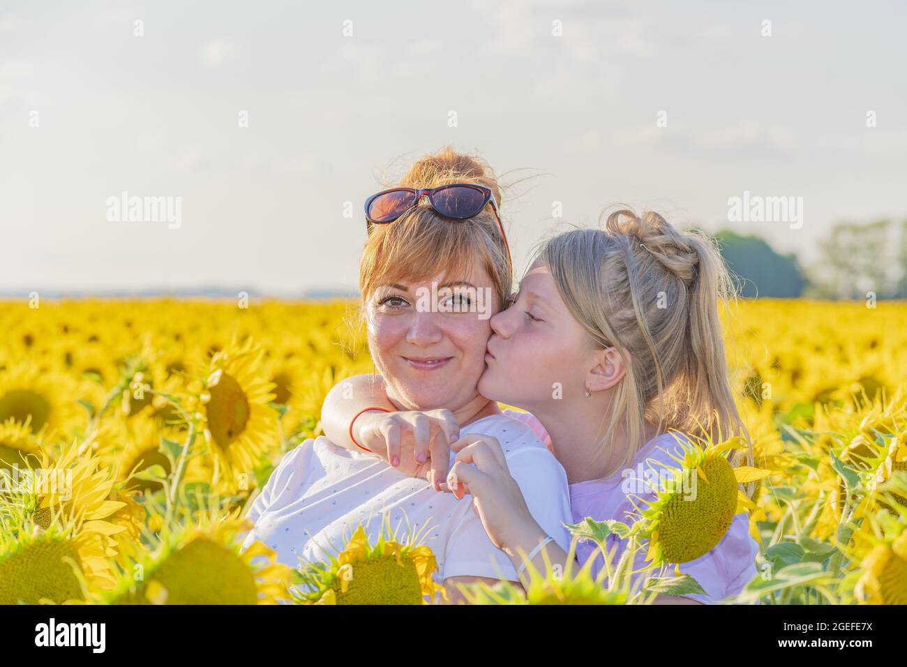 Girl hugs her mother by the neck and gently kisses her on the cheek. Children's love for parents. Stock Photo