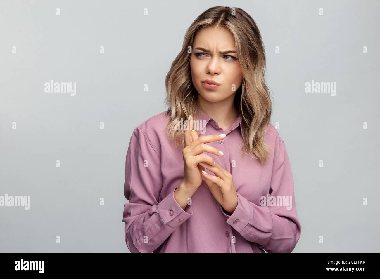Confused young woman look aside with doubtful and suspicious emotion thoughtful bending fingers Stock Photo