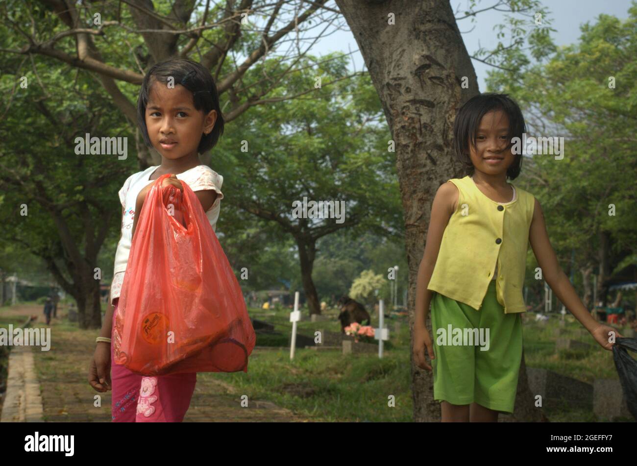 Portrait of children who are working by collecting plastic waste at Pondok Kelapa public cemetery in East Jakarta, Indonesia. Some of them work on daily basis; mostly by offering service of grave cleaning. Stock Photo