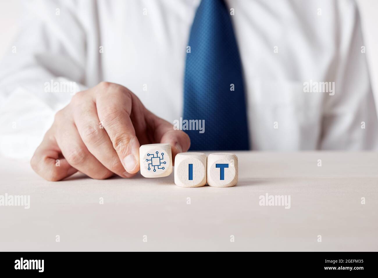 Hand of a businessman placing the wooden cubes with the word IT information technologies. Business management concept. Stock Photo