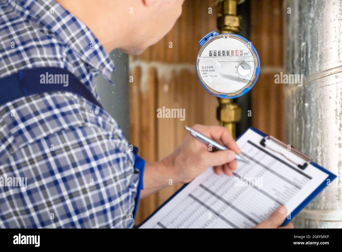 Technician With Clipboard Reading Water Meter Or Counter Stock Photo