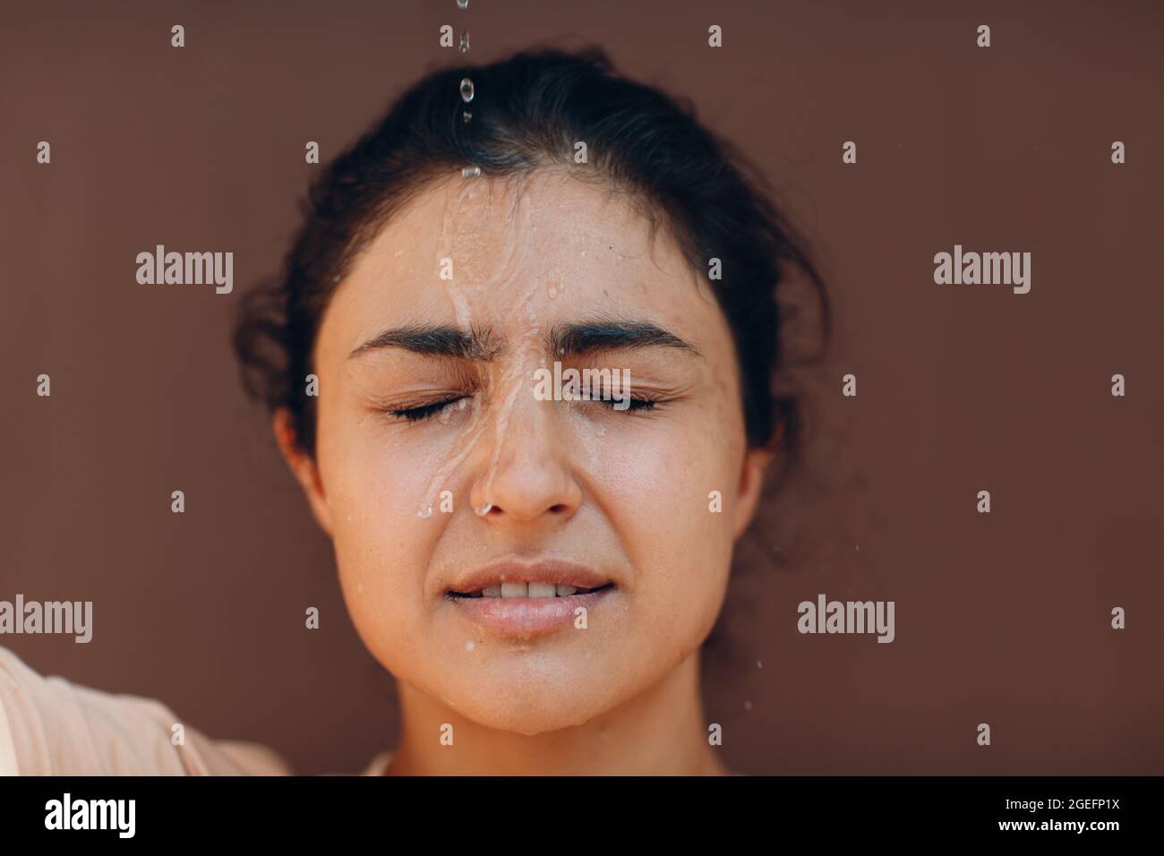 Stressed woman suffering of heatstroke and refreshing pouring with cold