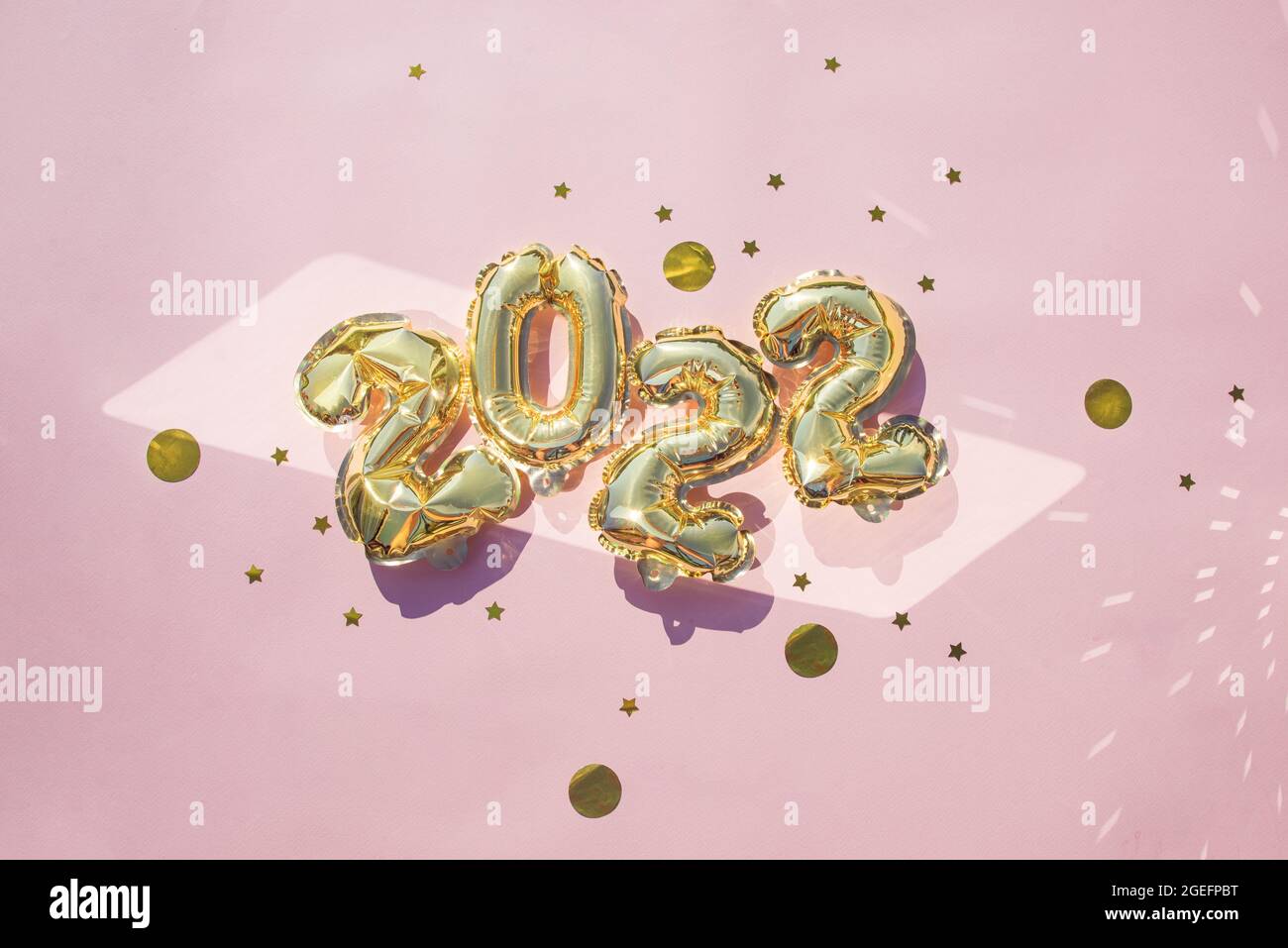 Gold balloons 2022 on a pink background, confetti, flat lay. New Years celebration concept Stock Photo