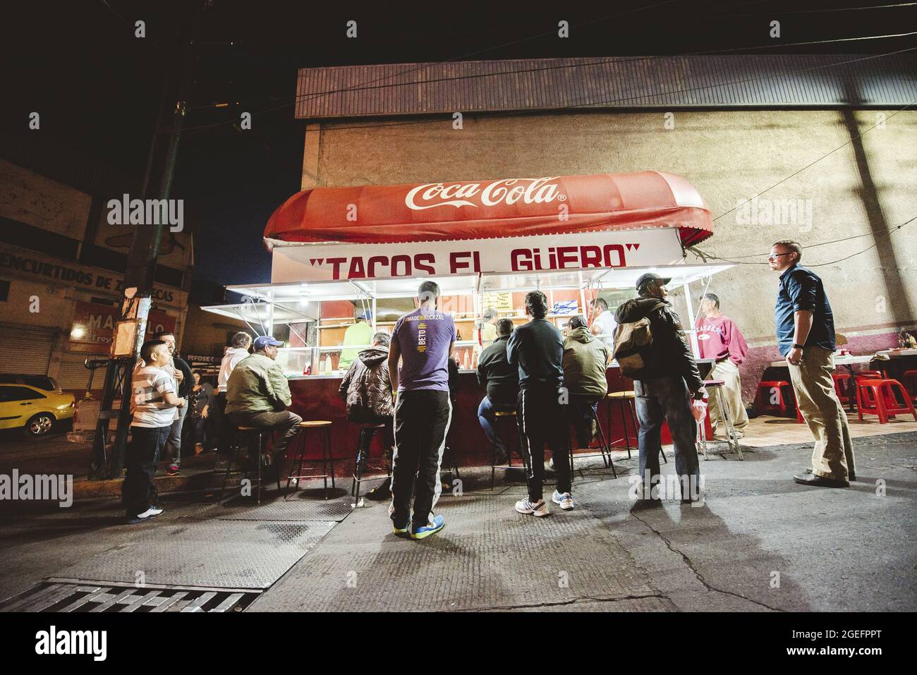 ZACATECAS, MEXICO - Apr 01, 2018: A group of people waiting in line and other people eating at a Mexican street food stall at night in Zacatecas, Mexi Stock Photo