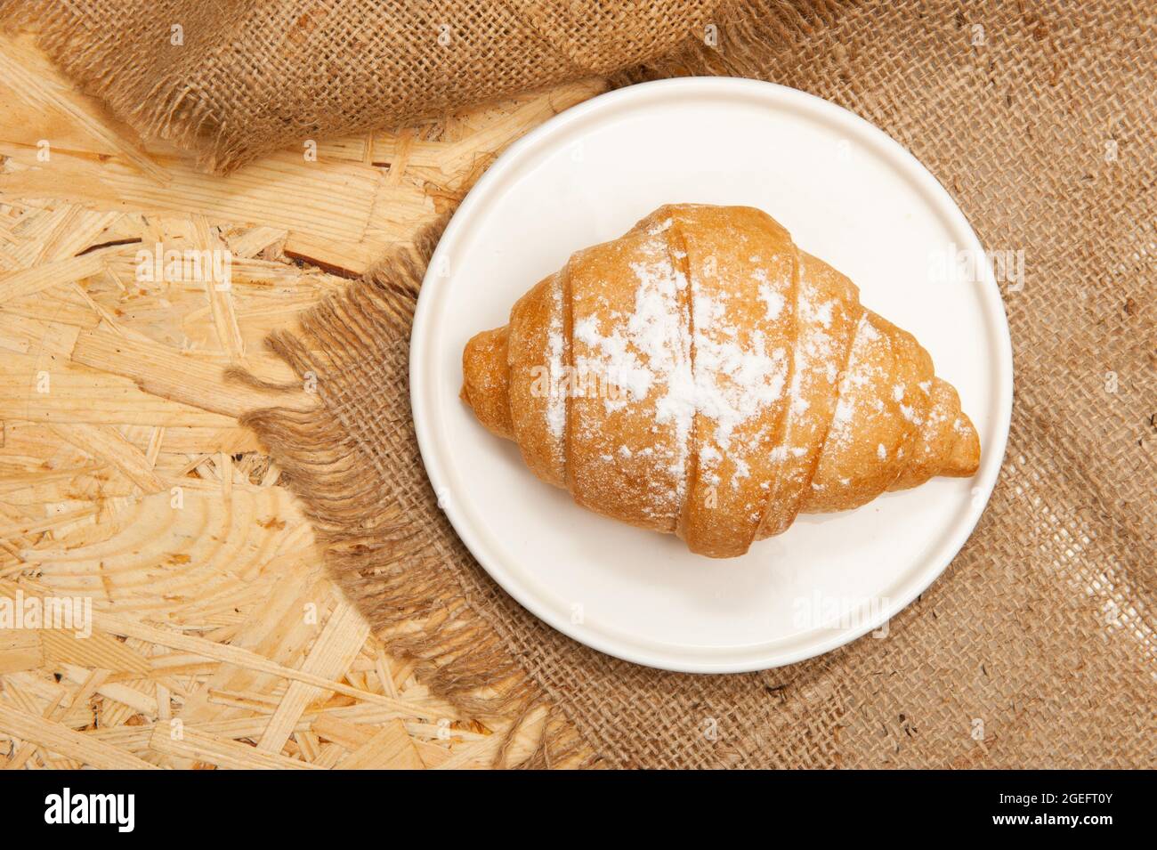 Croissant on a saucer and on a canvas napkin. Top view Stock Photo