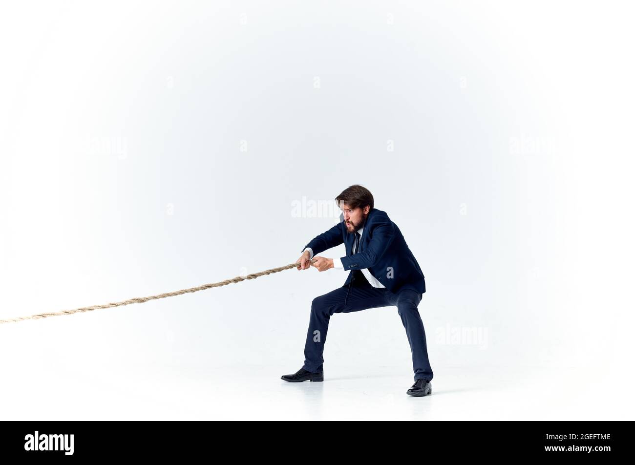 a man in a suit pulls the rope career office light background Stock ...