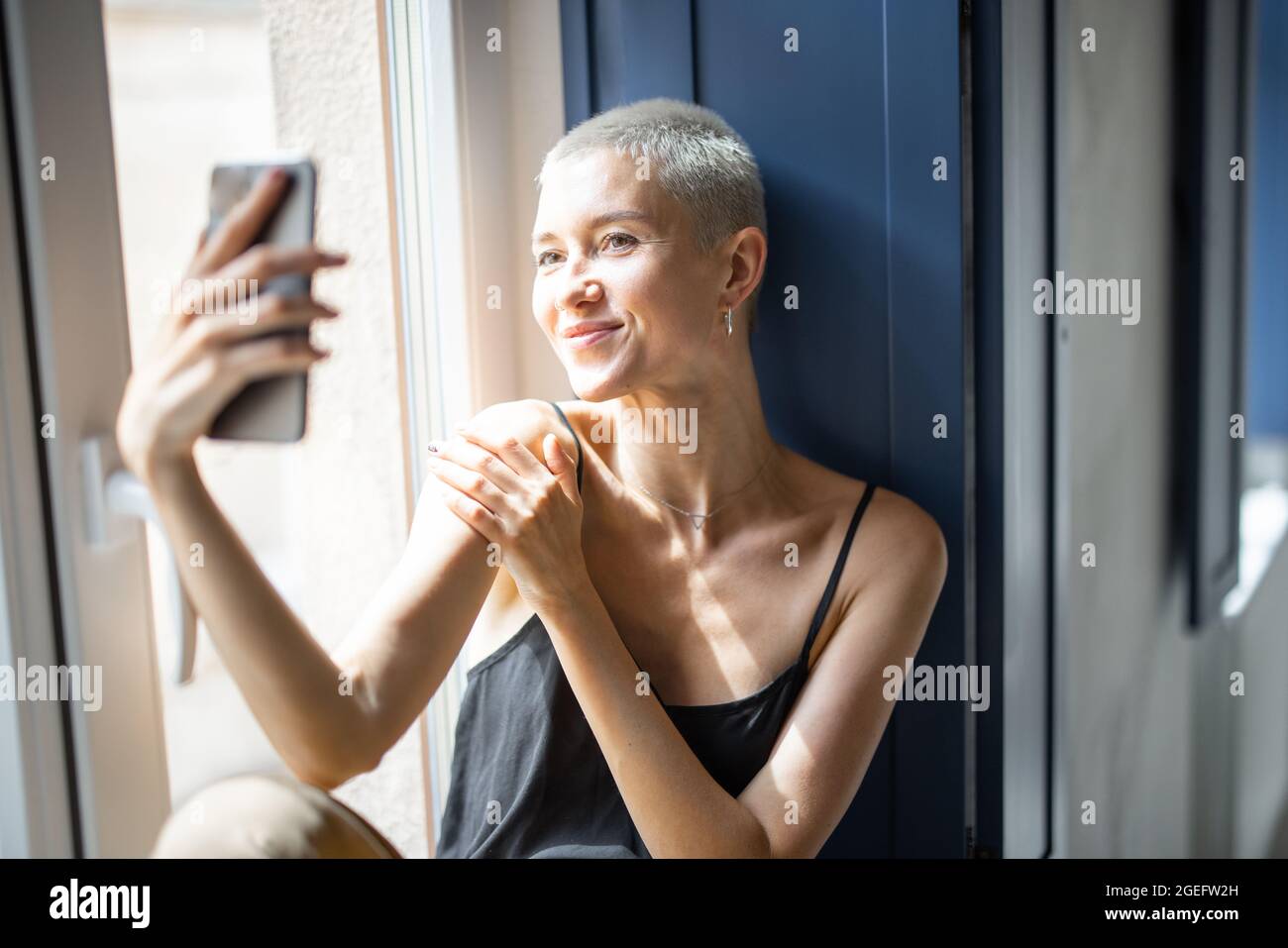 Stylish woman talking on phone at window Stock Photo