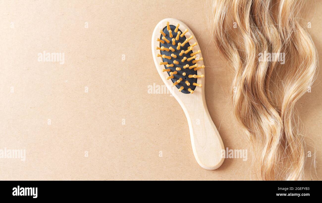 Beautiful blond female wavy hair lock and bamboo comb brush top view