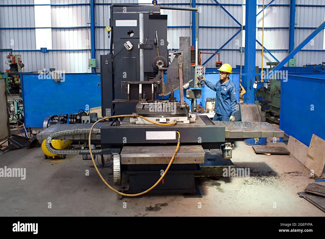 A worker is operating a horizontal boring and milling machine in a