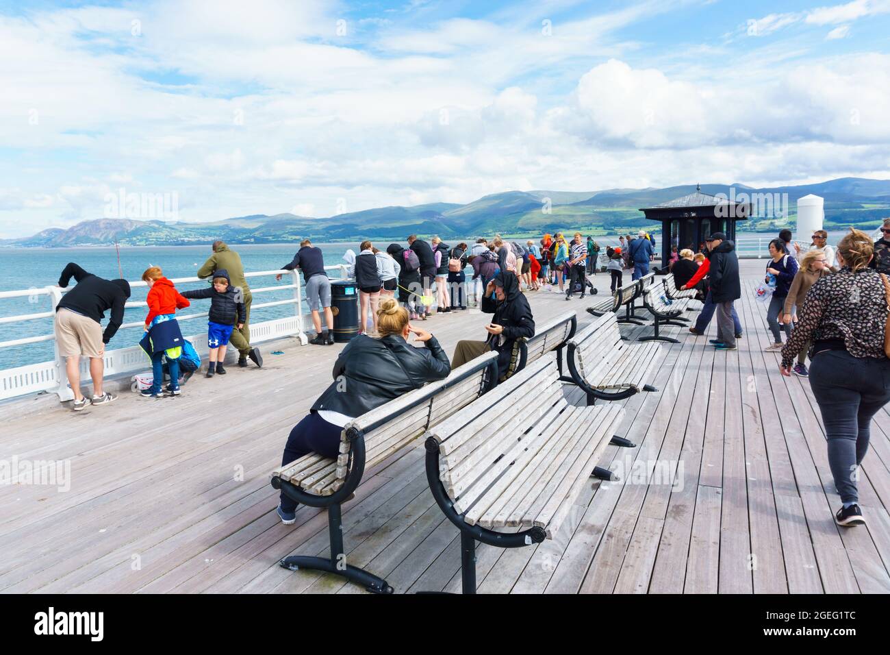 Tourists and visitors enjoying a summer afternoon on Beaumaris Pier a popular seaside tourist attraction on the Island of Anglesey Stock Photo