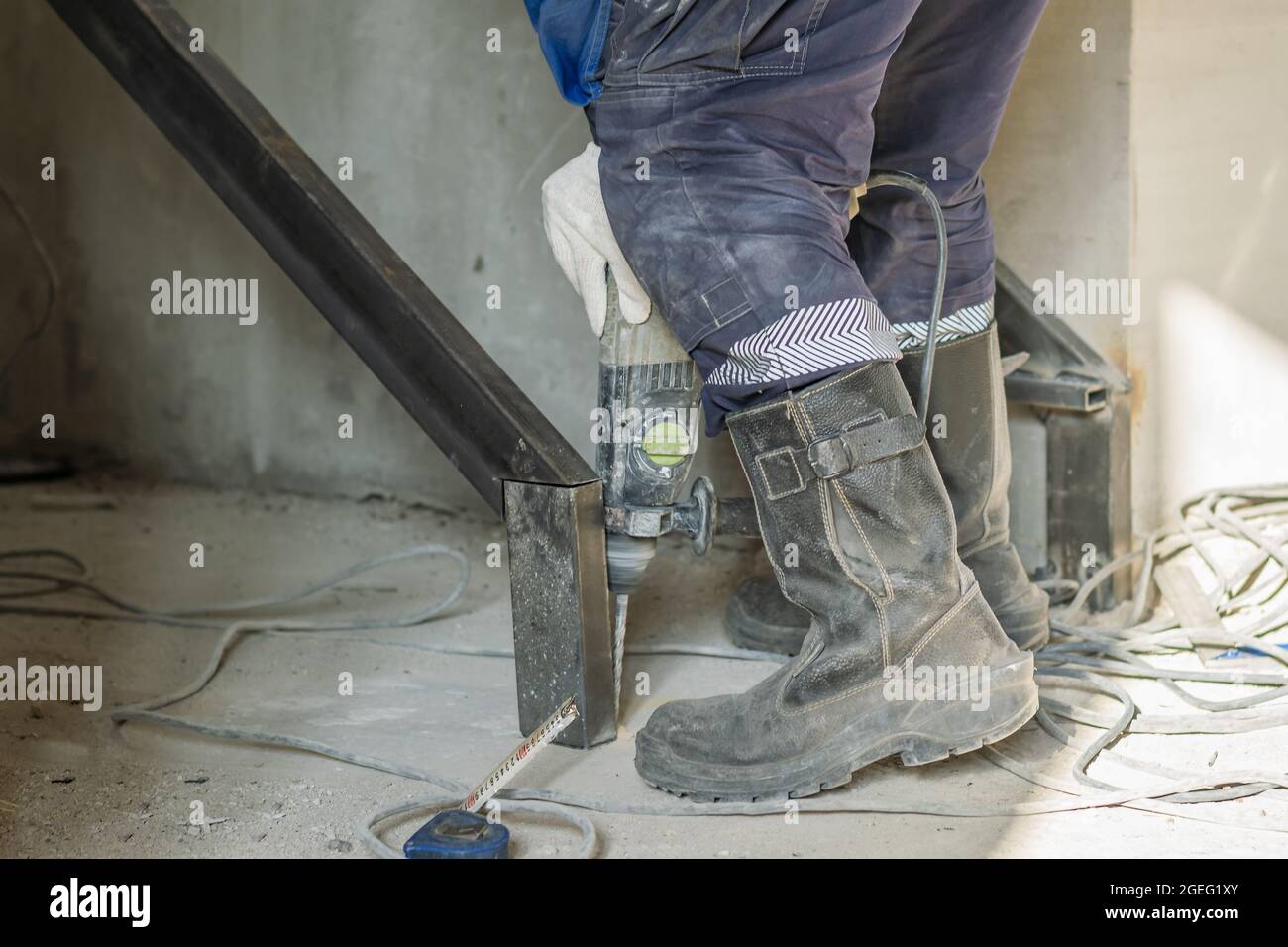 A construction worker drills holes in a concrete floor using an