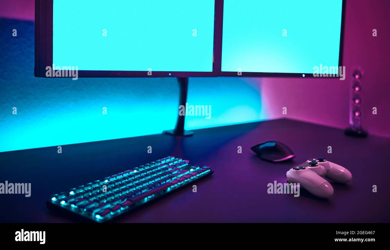 Computer input devices laying on table in front of two blank monitors ...